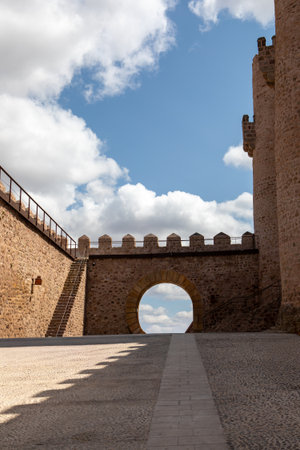 A beautifully constructed stone archway marks the entrance to an ancient fortress. Fluffy clouds provide a striking backdrop as the late afternoon sun casts soft shadows.の写真素材