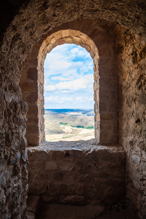 A breathtaking landscape unfolds from an arched stone doorway in Atienza, Guadalajara, Spain, revealing rolling hills and a river. The combination of nature and history captivates visitors.の写真素材