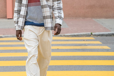 A well-dressed individual strides confidently across a yellow striped crosswalk. The urban backdrop...