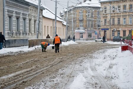 Two men workers clearing snow from the tram tracks のeditorial素材