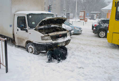 The driver of the car repairs lying in the snow Lviv Ukraine 15 03 2013のeditorial素材