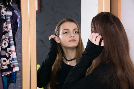 The girl at the mirror does makeup and hairstyle. The girl chooses an image.の写真素材
