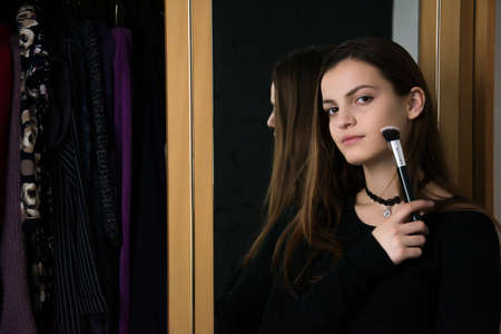 The girl at the mirror does makeup and hairstyle. The girl chooses an image.の写真素材