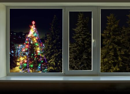 Bright lights on the Christmas tree outside the windowの写真素材