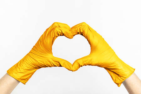 Hands in gold latex rubber gloves show heartの写真素材