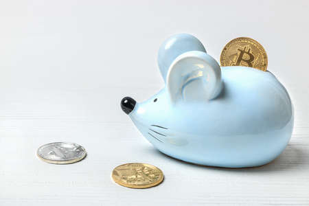Blue mouse piggy bank on a white background with bitcoin coins.の写真素材