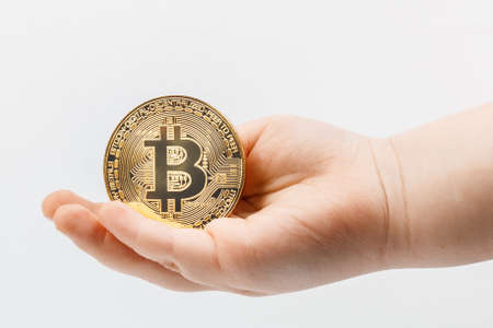 Closeup children's hand in the palm of which lies a bitcoin coin on a white background. Concept for articles and posts about the future and deposits in the bank.の写真素材