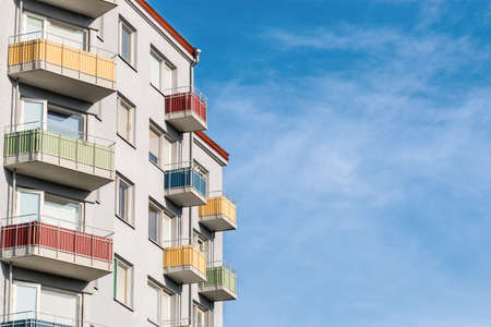 A light gray clean and tidy house building with colored balconies against a colorful blue sky. Concept for articles and posts on social networks about real estate and mortgage, with place for text.の写真素材