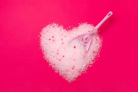 Cat litter, heart shaped bright pink background with a spatula for cleaning poop. Concept for labels, packaging advertising of the love of animal hosts to a neutralizing odor absorbent filler.の写真素材