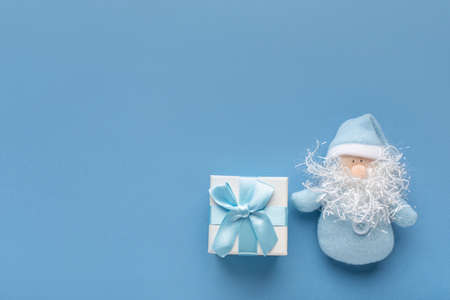 Beautiful delicate greeting Christmas New Year card in pastel blue color. Concept with place for text box with gift and bow and bearded Santa Claus.の写真素材