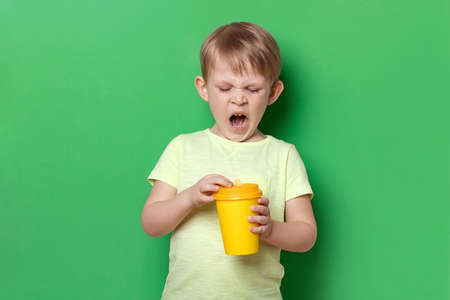 People child kid boy yawn open coffee yellow paper disposable cup. Concept of hard Monday morning,...