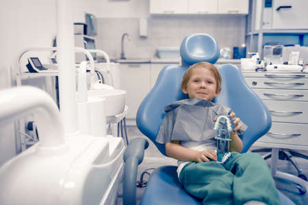 Caucasian child kid sit in dental chair at dentist doctor. Preschooler treating teeth, happy. Advertising concept with copy space.の写真素材