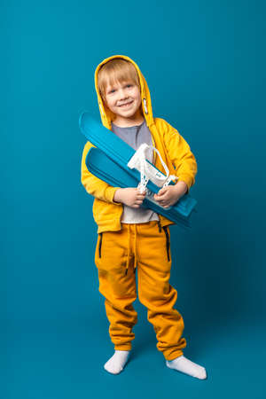 A child in a yellow sweatshirt with skis in his hands. Children's leisure and sports concept,...