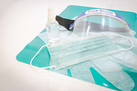 Face mask; disposable gloves; face shield and disinfectant on the green mat on white background table. Anti-Virus protection kit set.の写真素材