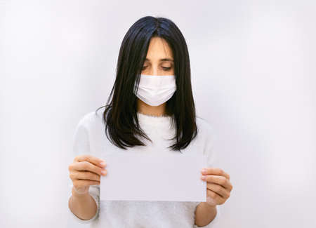 Attractive woman looks down and holds and shows in hand envelope  message isolated in whie background.の写真素材