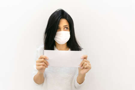 Attractive woman looks surprised straight and holds in hand white envelope with message isolated in white background. Blank space imageの写真素材