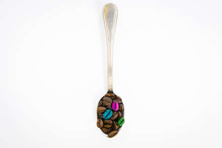 Colorful coffee beans in a spoon isolated in white background. Concept of creativity and different perspectiveの写真素材