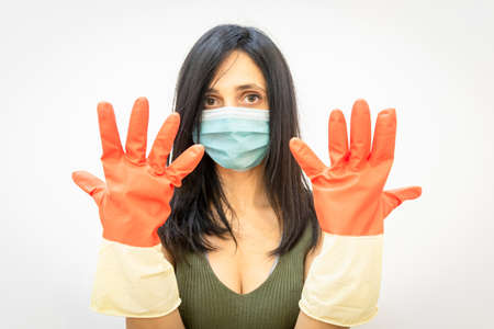 Beautiful and sexy woman with face mask on shows hands with big gloves  wearing. Safety; precautions...