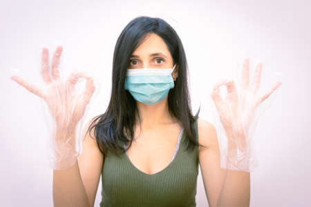 Close up of woman with face mask showsng okey sign with hands and looking straight. Concept of follow rules and pandemic regulation in public places.の写真素材