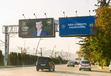 1 november, 2020. Tbilisi.Georgia.Parliament elections 2020 agitation.Giant billboard by the road  with passing cars. Georgian dreams party agitation poster with face of  Giorgi Gakharia.のeditorial素材
