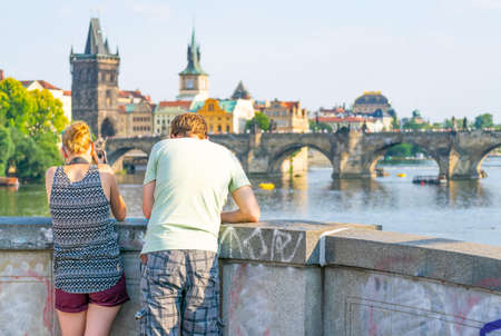 Male and female, a couple by the bridge standing and taking photographs with dslr camera of charles bridge in Prague.Chzech republic..の写真素材