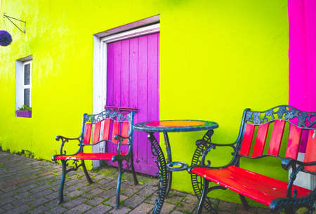 Colorful terrace set up with retro style chairs; table and green wall, purple entrance doorsの写真素材