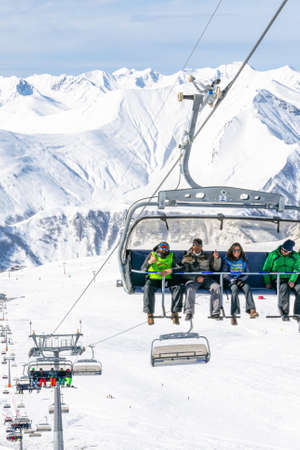 Ski instructors with custormer and paragliders team member sits on the chair lift in ski resort. Seasonal job concept and ski holidays. Gudauri. Georgia.28th February. 2020のeditorial素材