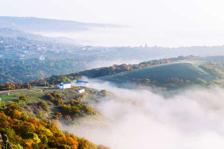 Panoramic view down to Saint George monastery in Kojori surounded by mist and clouds. Religion and...
