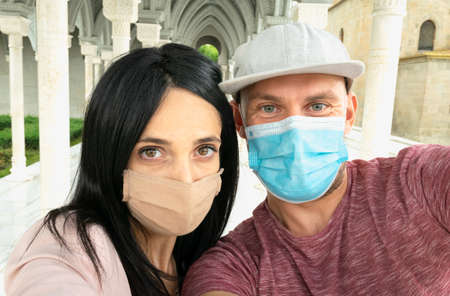 Close up Selfie of  happy multiracial couple faces with masks on i na public place. Natural...