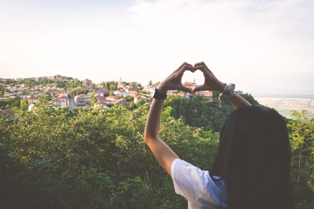 Cute woman makes heart shape hand with love city sighnaghi panorama.Faded filterの写真素材