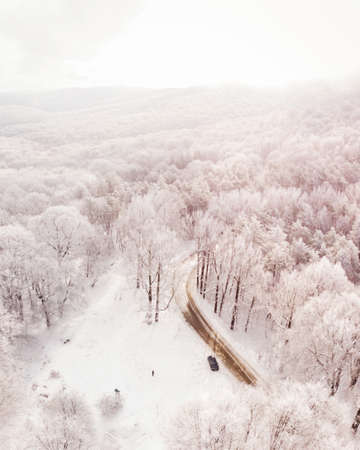 Aerial view snowy forest with road and car standing parked. Road trip caucasus winter concept....