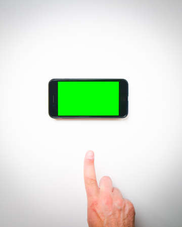 Male hand finger up to smartphone green screen on a white background curtains. Isolated blank space...