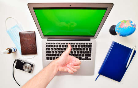 Desktop green screen computer with blue notebook, globe stand, passport, compact camera and hand...