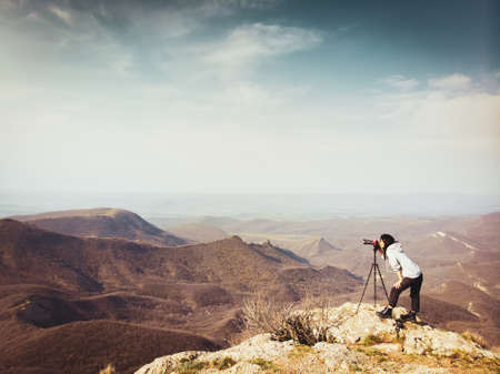 Side view young brunette caucasian woman travel photographer shooting landscape photo outdoor. New millennial photographers shooting landscapes on field.の写真素材