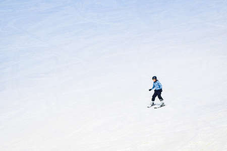 Young caucasian Teenager boy with no jacket skiing down hill on ski slope