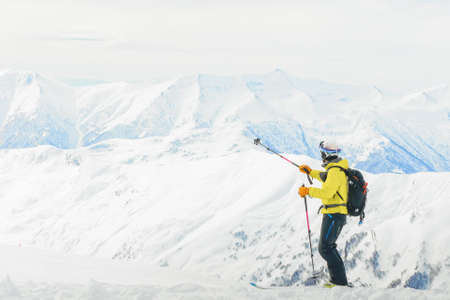 Male skier point to snowy mountain peaks with stick outdoors in winter holiday adventureの写真素材