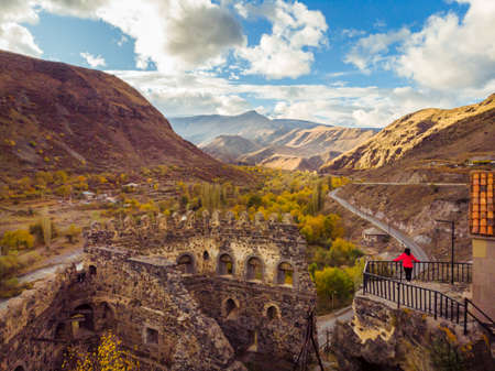 Girl ir red jacket standing on viewpoint of Khertvisi castle and looking to stunning panorama of caucasus mountains. Stunning sightseeing places in Georgia. Travel in caucasus.の写真素材