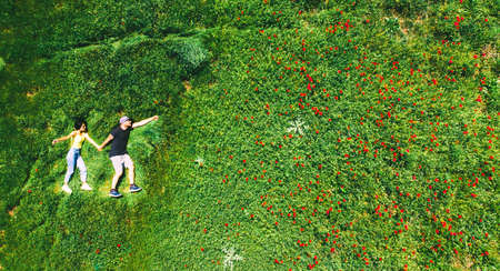 happy couple together in love isolated laying in green nature field on summer day. Top view fun in relationship couple copypaste backgroundの写真素材