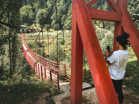 Tourist by red old metal structure with wooden pathway bridge in nature in Georgia countryside. Adjara hidden gemsの写真素材