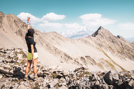 Caucasian woman stand on rocky Deda ena viewpoint. Carefree tourist woman looking at sun enjoying landscape. Girl traveler on top of summit Deda ena enjoy panorama of KAzbegiの写真素材