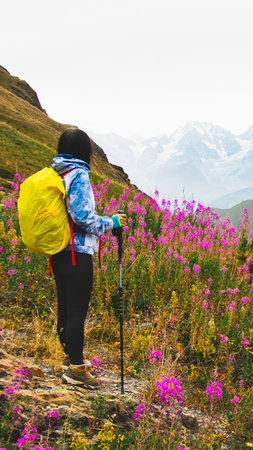 Young fit happy woman stand on viewpoint after reach top in mountains. Carefree tourist woman looking at sun enjoying landscape. Girl traveler on top of mountain in rays of sunsetの写真素材