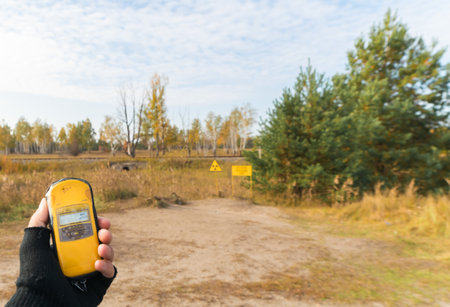 Yellow geiger counter on the hands shows blank space level near radiation symbol in front of red...