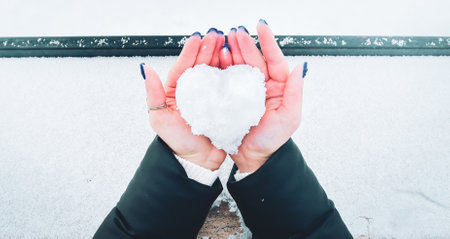 Top down view woman in two hands hold ice heart made of snow. Girl give heart on valentines dayの写真素材