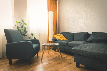 Cozy apartment living room with sofa and yellow pillows and stylish table with book by flower and...