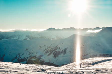Caucasus mountains wide panorama in sunny day with snow crystals in air and skier stand enjoy holidays on piste. Gudauri Georgia travel winter destinationの写真素材