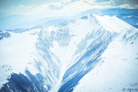 People paragliding tandem above mountain in winter in Georgia ski resort. Concept of active...