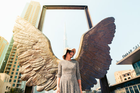 Dubai, UAE - 12th october, 2022: female caucasian tourist pose by The Wings of Mexico modern sculpture by Jorge Marin and Burj Khalifa building in the backgroundのeditorial素材