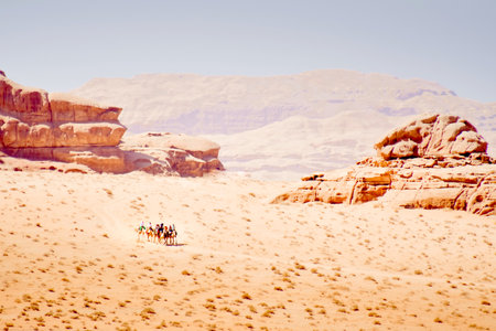 Group of tourist ride on camel caravan in wadi rum desert with scenic rock formations panoramaの写真素材