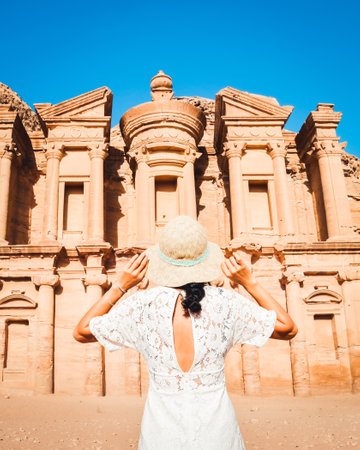 Cinematic Petra background caucasian young woman in white dress and hat enjoying Petra A'deir Monastery, Petra's largest monumentの写真素材