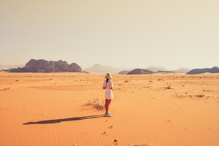 Woman tourist stand on cliff at viewpoint enjoy Wadi rum panorama on sunrise. Wadi Rum desert - valley Wadi Saabit. Jordan explore conceptの写真素材